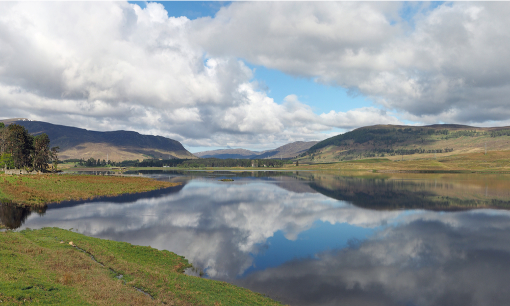 Spey river west of the dam with hills and clouds reflections, Scotland in spring